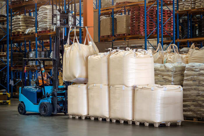 Warehouse operative moving bulk bags with a forklift